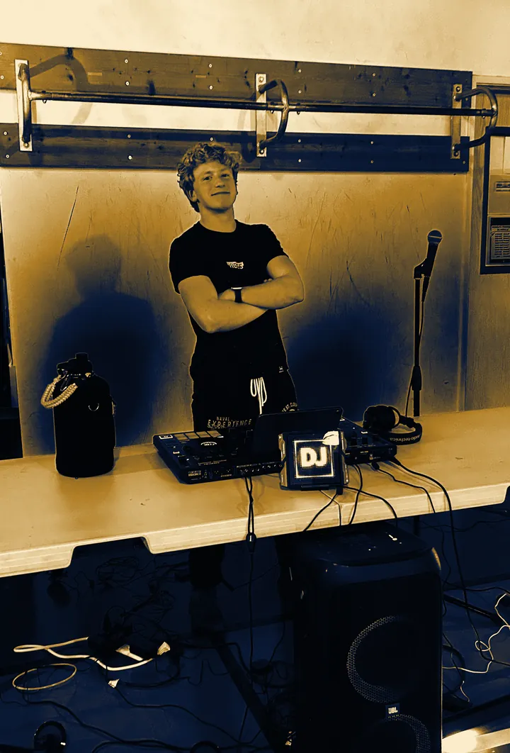 DJ Zion with arms crossed behind his DJ setup