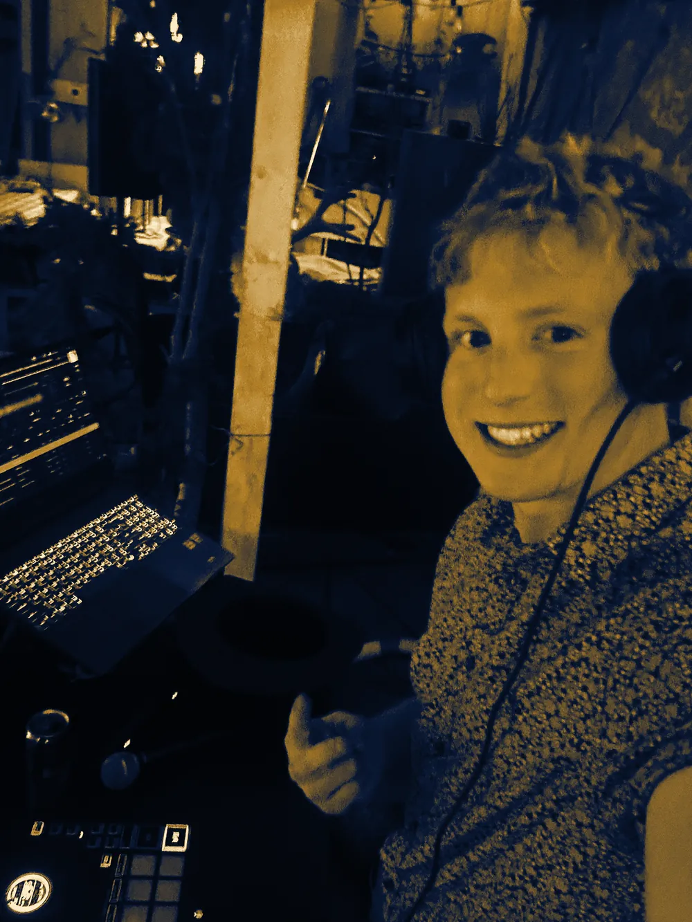 DJ Zion grinning at the camera from behind the decks, headphones on