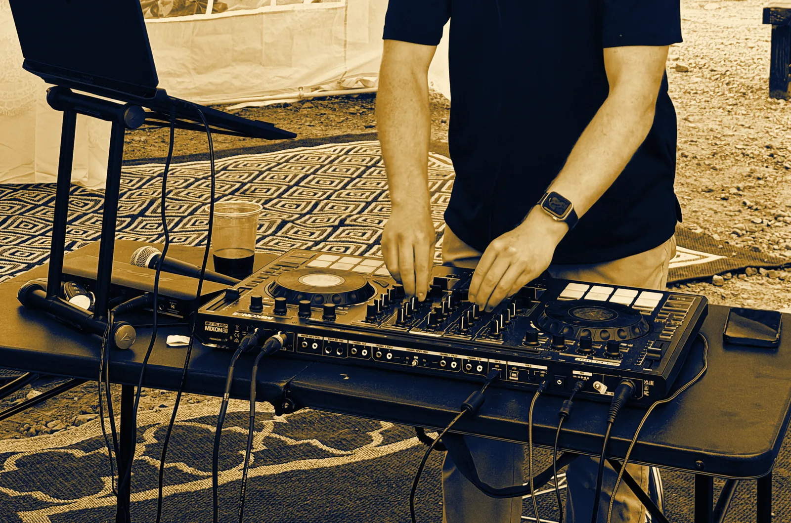 DJ Zion's hands on the Mixon 8 Pro controller at an outdoor wedding tent